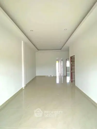 Spacious empty room with tiled flooring and high ceiling, perfect for customization.