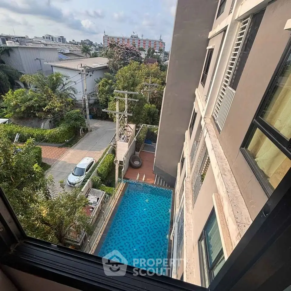 High-rise apartment view overlooking a serene swimming pool and lush greenery.