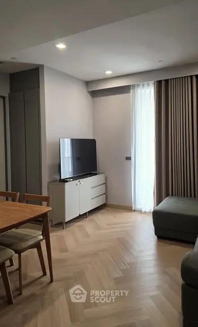 Modern living room with sleek furniture and natural light, featuring a stylish TV setup and elegant flooring.