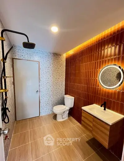 Modern bathroom with stylish tiles and elegant fixtures, featuring a round mirror and sleek showerhead.