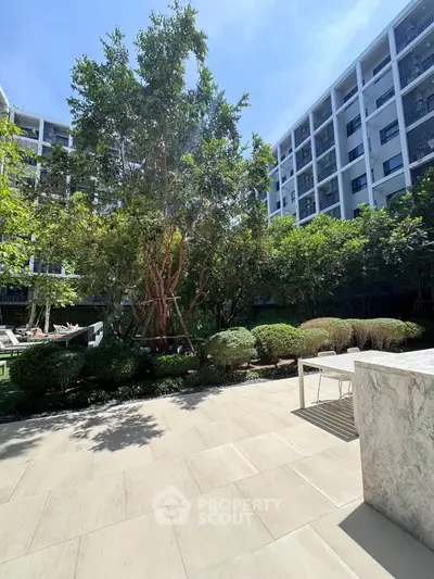 Modern apartment complex with lush garden and outdoor seating area, perfect for relaxation.
