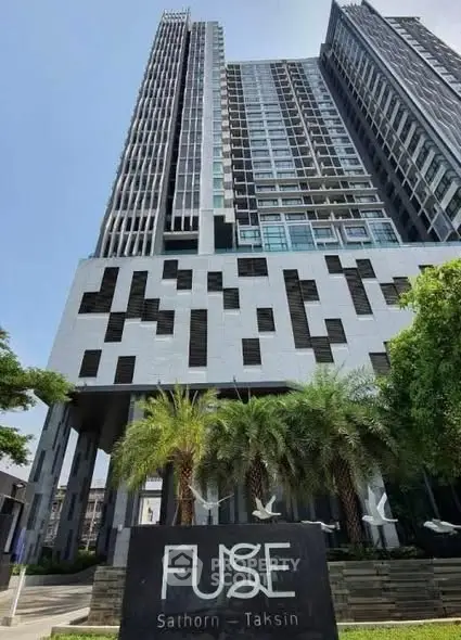Modern high-rise building with unique facade design and lush landscaping at Fuse Sathorn-Taksin.