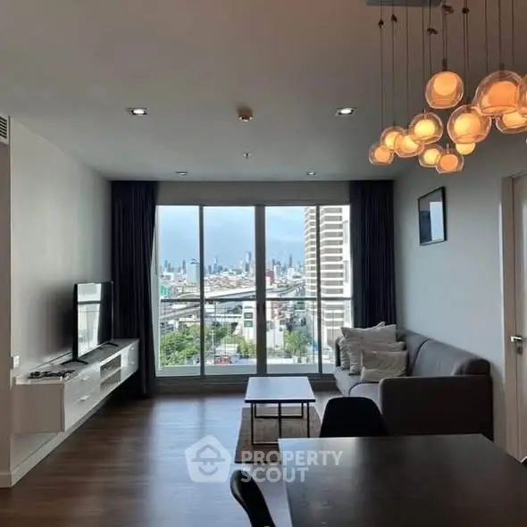 Modern living room with city view, stylish lighting, and sleek furniture in a high-rise apartment.