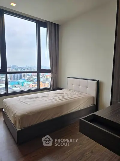 Modern bedroom with city view, featuring sleek furniture and large windows for natural light.