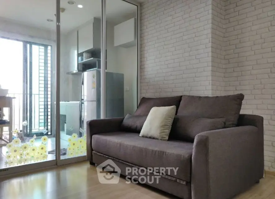 Modern living room with cozy sofa and stylish brick wall, adjacent to a bright balcony.