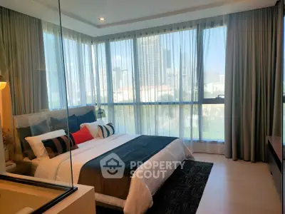Luxurious bedroom with floor-to-ceiling windows offering stunning city views, modern decor, and elegant furnishings.
