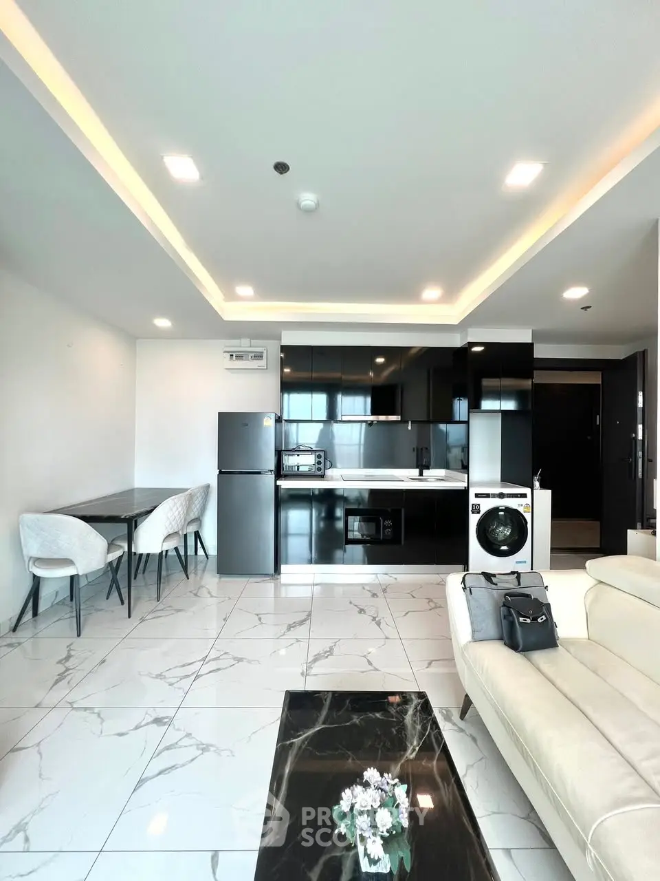 Modern open-plan living room with sleek kitchen and dining area, featuring marble flooring and contemporary furniture.
