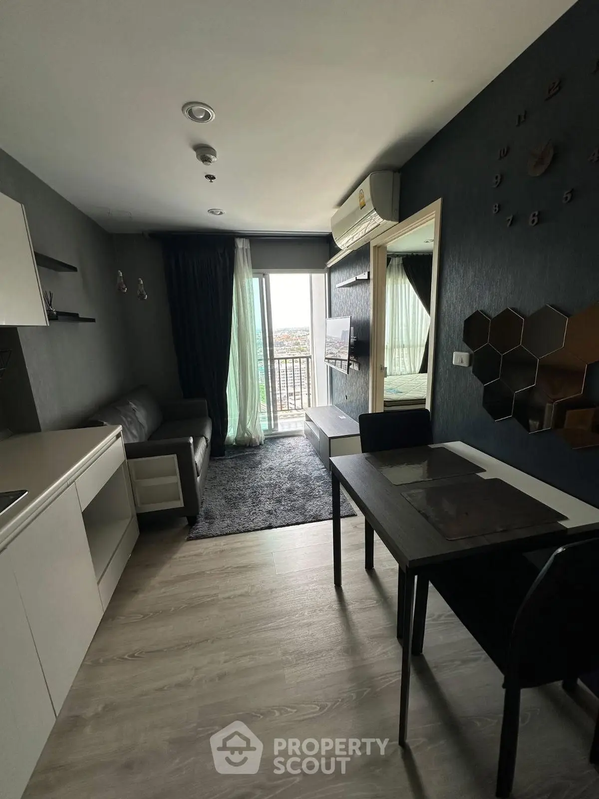 Modern living room with balcony view, sleek furniture, and stylish decor in a compact apartment.