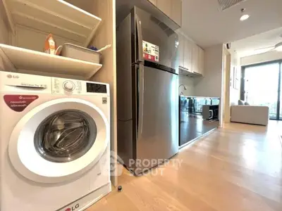 Modern kitchen with stainless steel fridge and washing machine in open layout apartment.