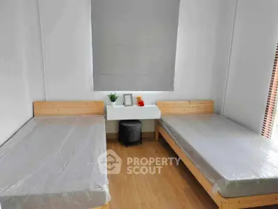 Modern bedroom with two single beds and minimalist decor, perfect for a cozy living space.