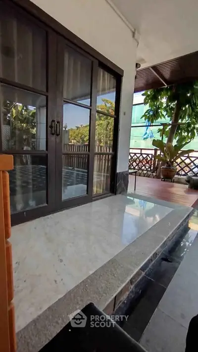 Charming balcony with lush greenery and sliding glass doors, perfect for relaxation.