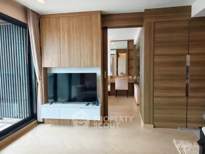 Modern living room with wooden accents and large TV, featuring a sliding door to a study area.