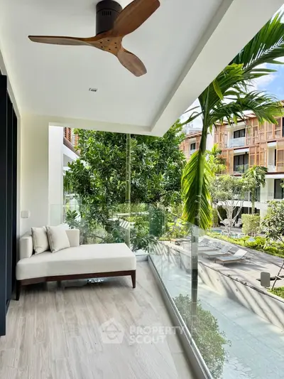 Luxurious balcony with modern seating and lush garden view in upscale residential complex.
