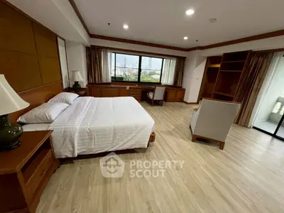 Spacious bedroom with city view, featuring elegant wooden furniture and large windows.