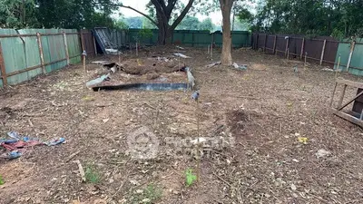 Vacant land plot with trees and fencing, ideal for development or gardening.