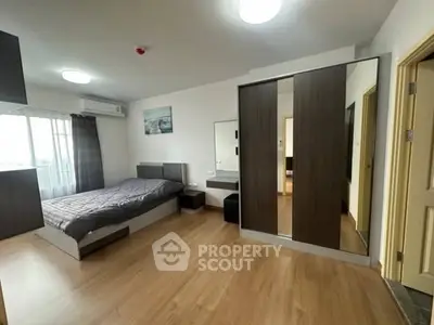 Spacious modern bedroom with sleek wooden flooring and large mirrored wardrobe