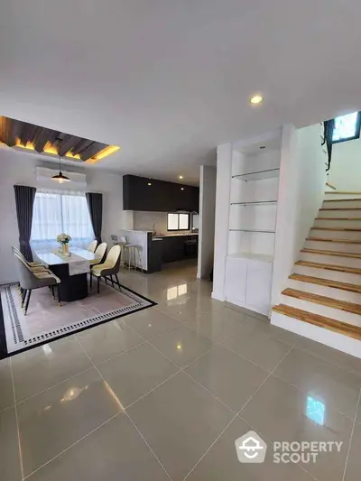 Modern open-plan dining area with sleek kitchen and stylish staircase