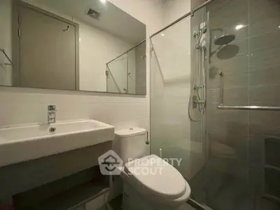 Modern bathroom with sleek fixtures and glass shower enclosure in a contemporary apartment.