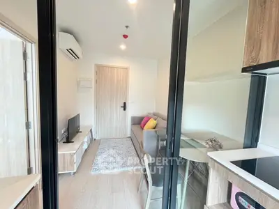 Modern living room with sleek furniture and glass dining table in a cozy apartment.