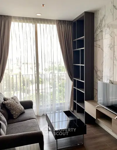 Modern living room with large window, elegant curtains, and stylish furniture