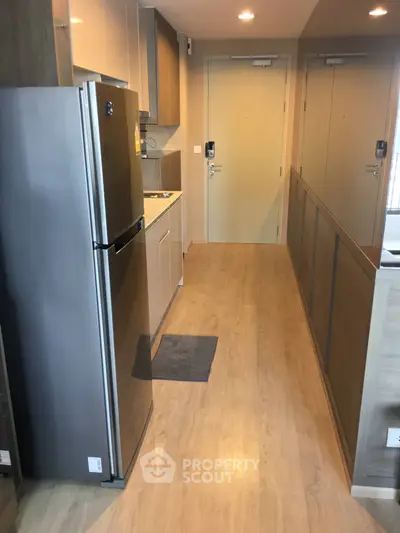 Modern kitchen with sleek appliances and wooden flooring in a compact apartment