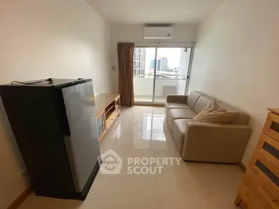 Cozy living room with modern sofa, fridge, and balcony view in urban apartment.