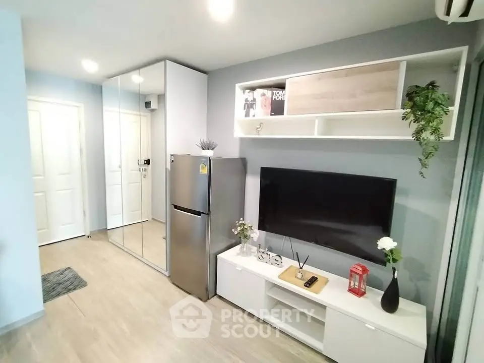 Modern living room with sleek decor, mirrored closet, and wall-mounted TV in a stylish apartment.