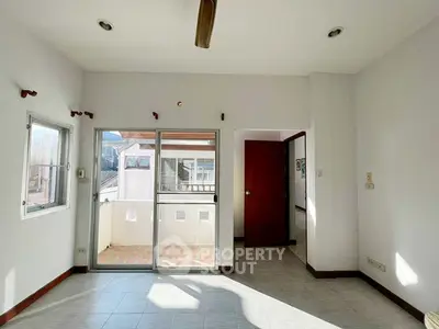 Bright room with balcony access and tiled flooring, ideal for versatile living space.
