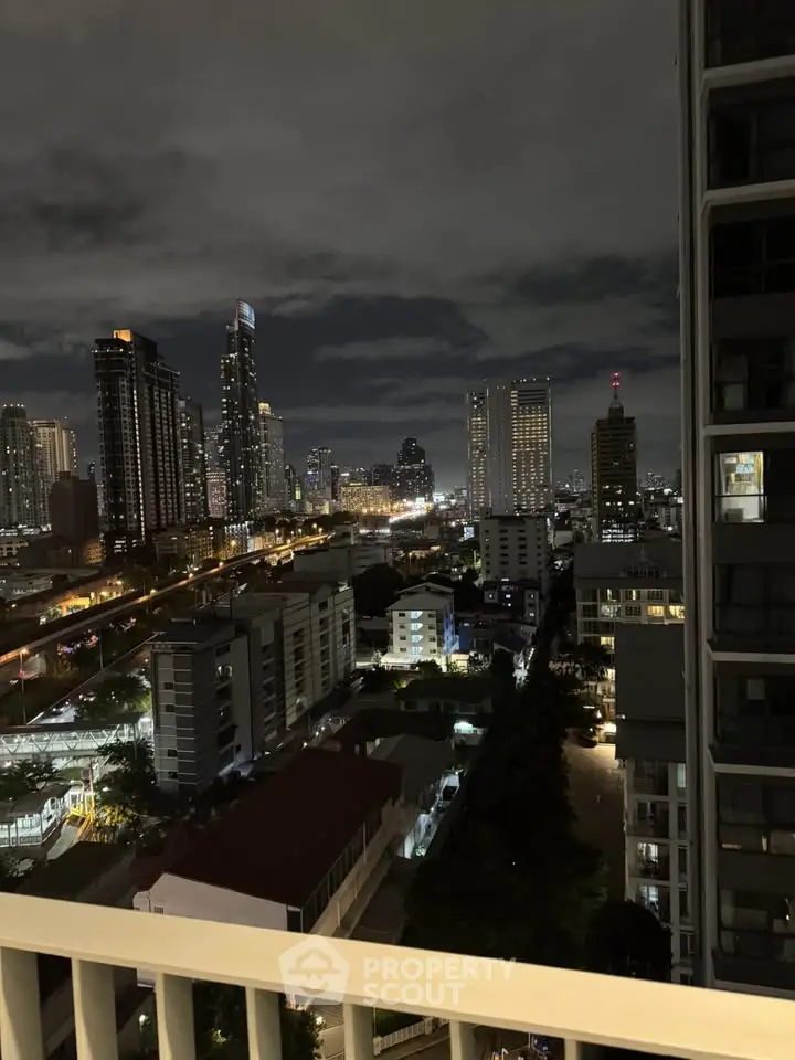 Stunning city skyline view from a high-rise balcony at night, showcasing vibrant urban lights.