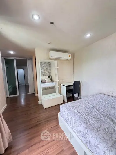 Modern bedroom with wooden flooring, stylish bed, and study desk in a cozy apartment.