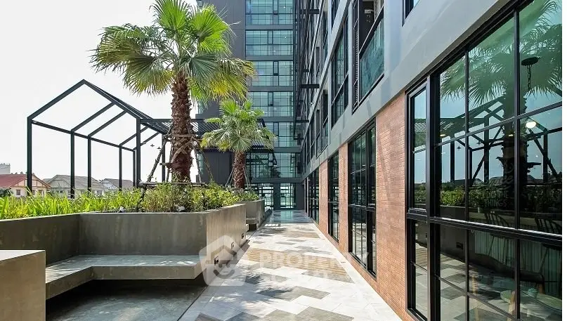Modern building exterior with lush garden and sleek architectural design.