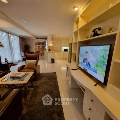 Spacious living room with modern open kitchen and large TV, perfect for entertaining.