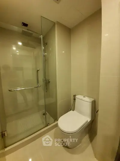 Modern bathroom with glass shower and sleek toilet in a contemporary apartment.