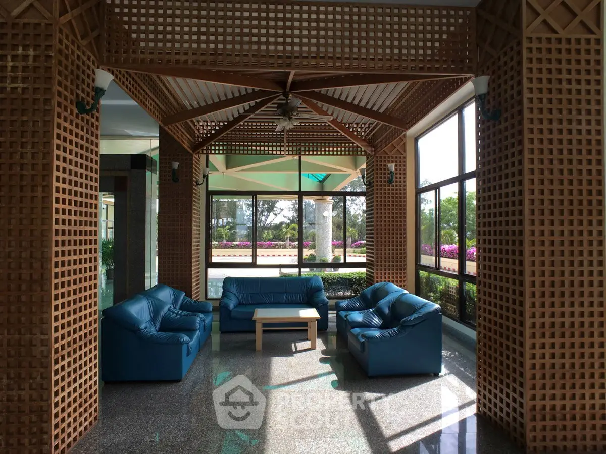 Luxurious sunlit lounge area with blue leather sofas and wooden lattice design, perfect for relaxation.