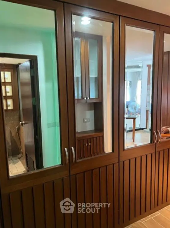 Elegant wooden closet with glass doors in a modern interior setting.