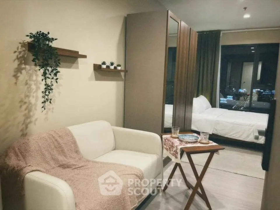 Cozy studio apartment with modern decor and city view, featuring a comfortable sofa and stylish bedroom.