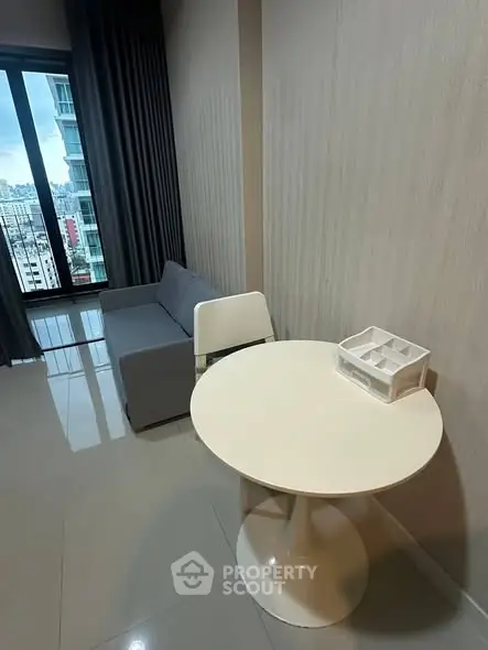 Modern living room with city view, featuring sleek furniture and large windows.