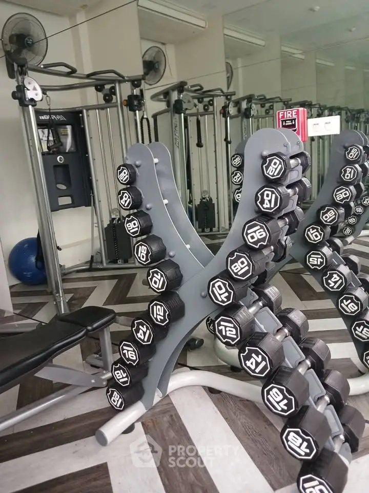 Modern gym with dumbbells and fitness equipment in a stylish interior.