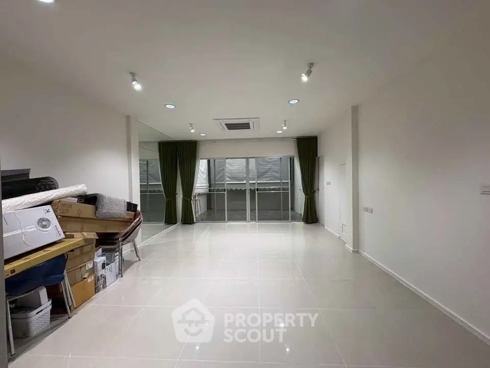 Spacious unfurnished living room with large windows and tiled flooring.