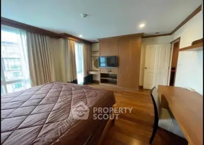 Spacious bedroom with wooden flooring and built-in wardrobe in modern apartment