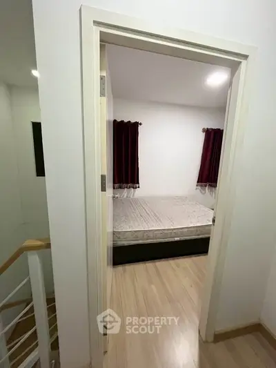 Cozy bedroom with wooden flooring and natural light, perfect for relaxation.