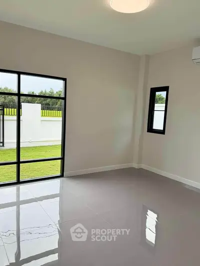 Spacious empty room with large windows and garden view, perfect for customization.