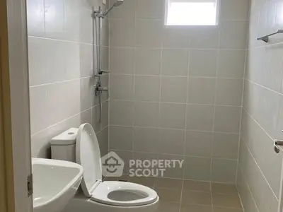 Modern bathroom with sleek fixtures and neutral tiles, featuring a shower and toilet.