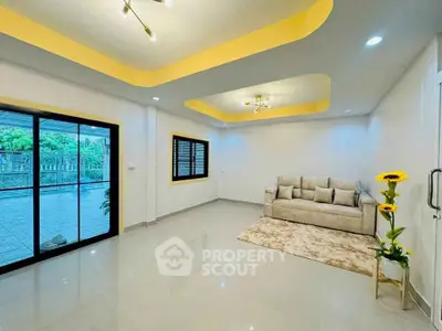 Spacious living room with modern lighting and large windows overlooking a garden.