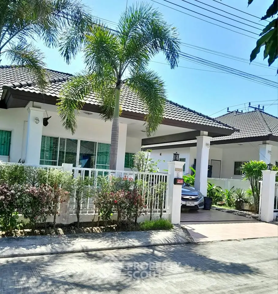 Charming single-story house with lush garden and driveway in tropical setting.