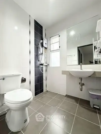 Modern bathroom with sleek fixtures and large mirror in a bright, tiled space.