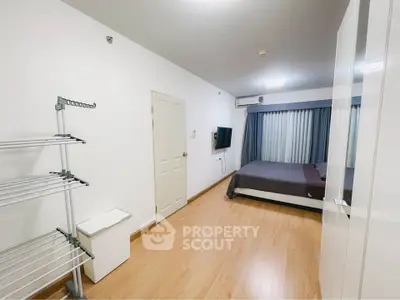 Modern minimalist bedroom with wooden flooring and wall-mounted TV