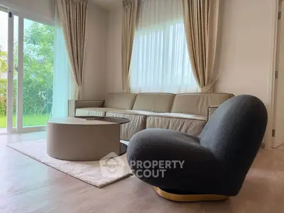 Elegant living room with modern furniture and large windows overlooking a lush garden.