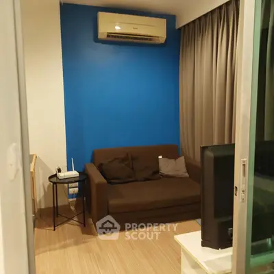 Cozy living room with brown sofa, blue accent wall, and air conditioning unit.