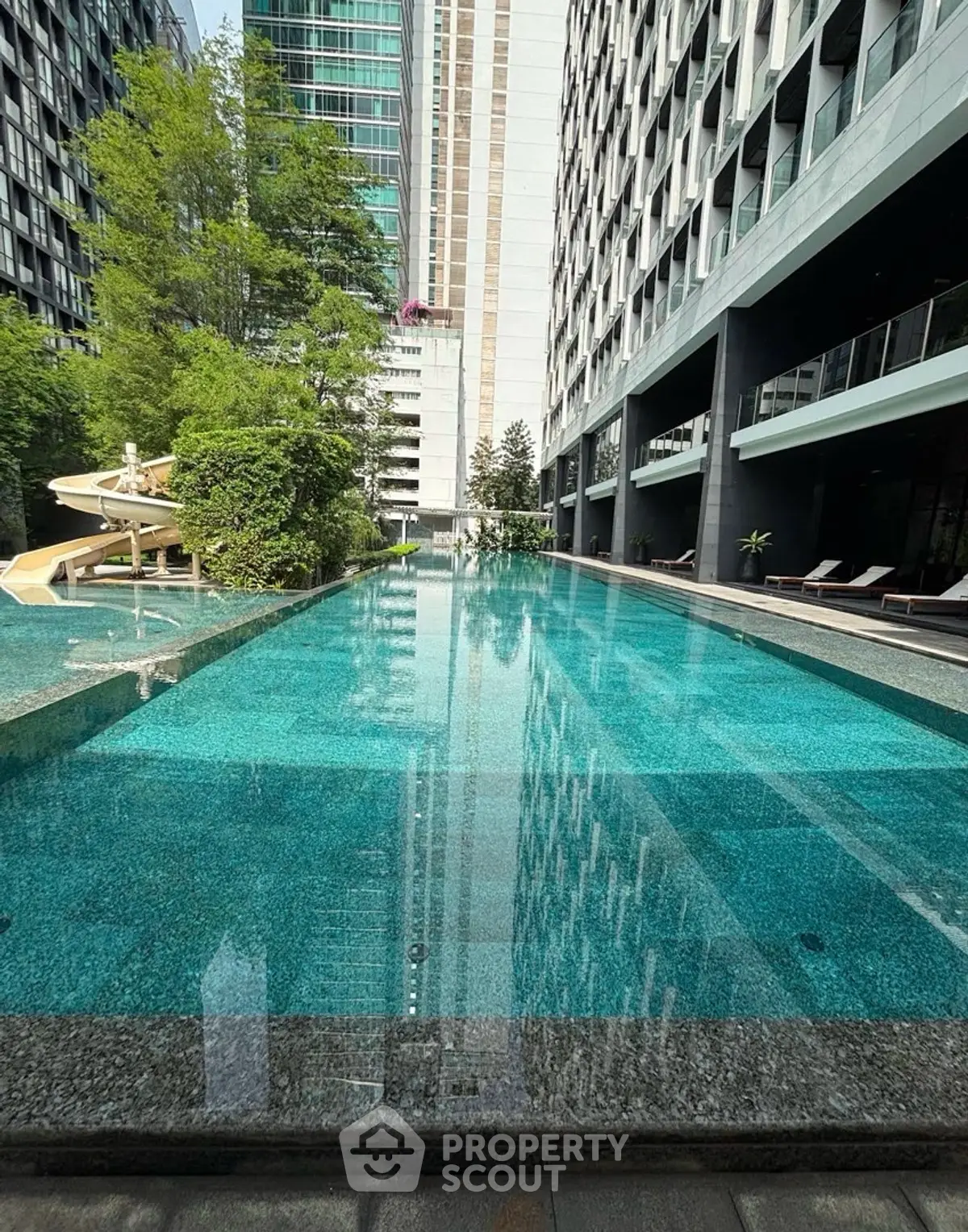 Luxurious modern apartment complex with stunning outdoor pool and lush greenery.